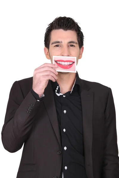 Человек в костюме держит фотографию губ у рта — стоковое фото