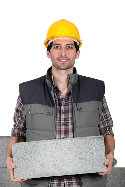 Jovem pedreiro carregando um bloco de cimento — Fotografia de Stock