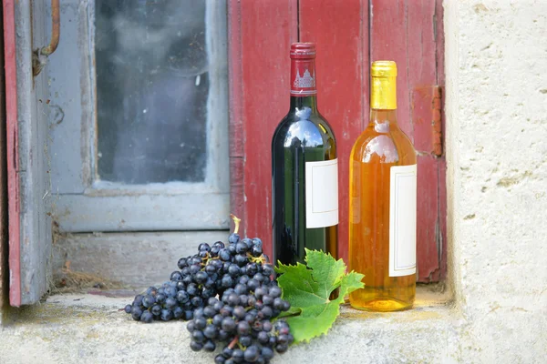 Two bottles of wine on rustic windowsill — Stock Photo, Image