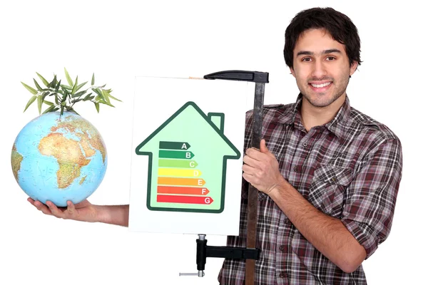 Ремісник тримає етикетку енергоспоживання і глобус з зеленою рослиною на ньому — стокове фото