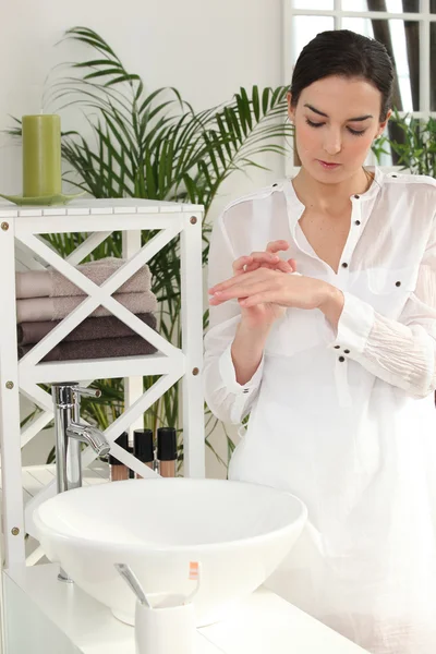 Vrouw toepassing lotion op haar handen — Stockfoto