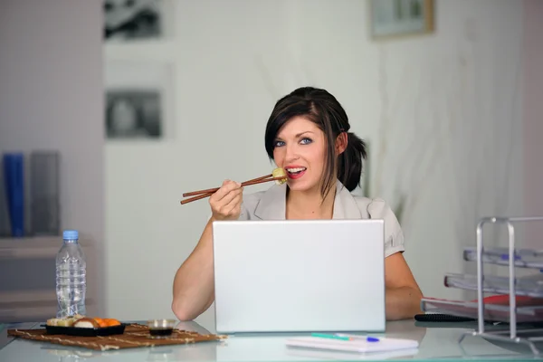 Frau isst vor dem Computer — Stockfoto
