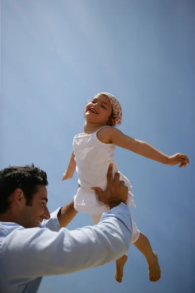 Vader dochter tegen een blauwe hemel opheffen — Stockfoto