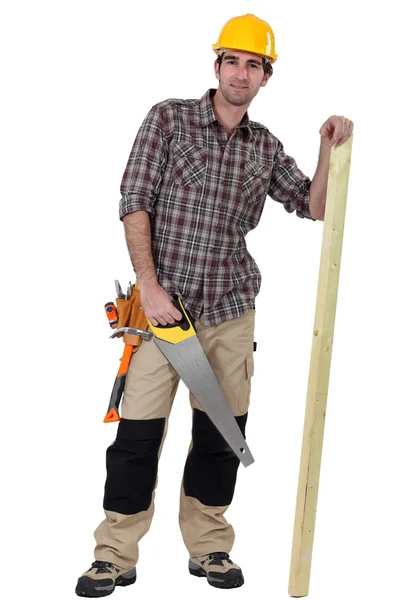 Tradesman com uma serra e uma prancha de madeira — Fotografia de Stock