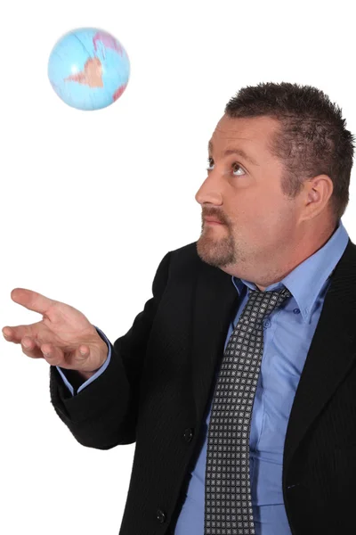Mann in Mantel und Krawatte spielt mit Globus — Stockfoto