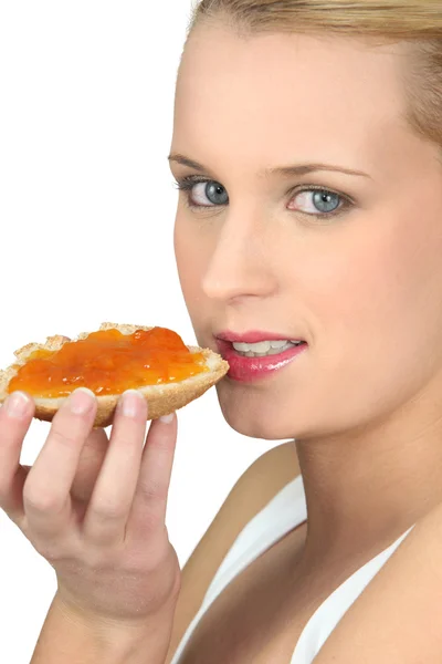 Mujer comiendo un pedazo de pan con mermelada — Foto de Stock