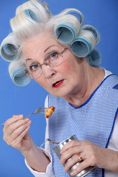 Funny grandmother eating canned food with fork — Stok fotoğraf