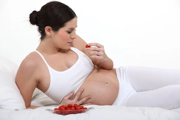 Schwangere Brünette isst Erdbeeren — Stockfoto