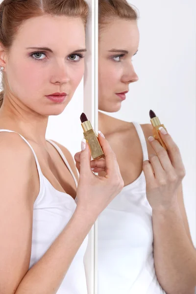 Junge Frau trägt Lippenstift im Spiegel auf — Stockfoto