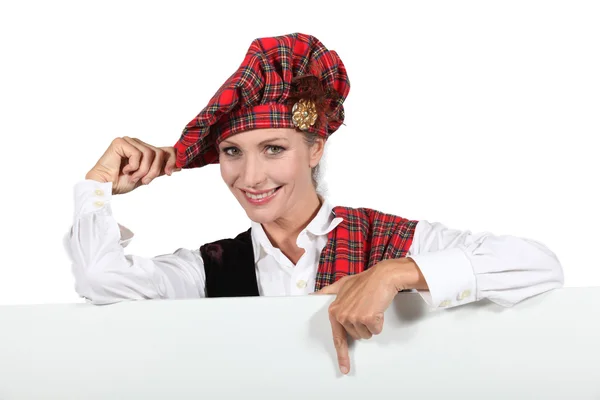 Schotse woman wijzend op wit bord — Stockfoto