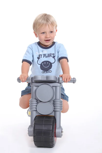 Un niño pequeño en su moto de juguete . — Foto de Stock