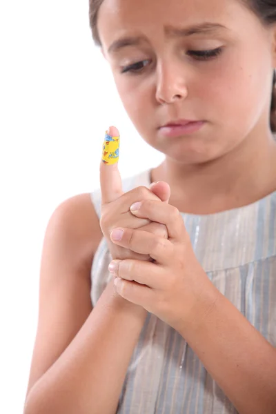 Küçük kız izlemek sargı bezi parmağına — Stok fotoğraf