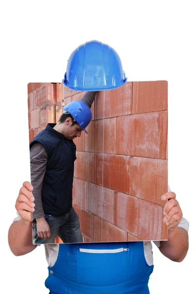 Builder hiding behind picture of construction site — Stock Photo, Image