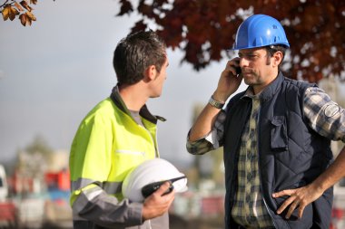 Construction workers on site with a phone clipart