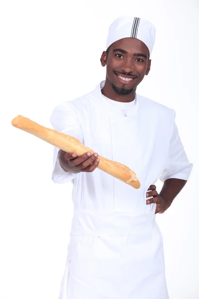 Young African baker holding a fresh baked bread — Stock Photo, Image