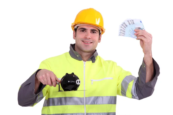 Šťastný řemeslníka držet peníze v hotovosti a bankou prase — Stock fotografie
