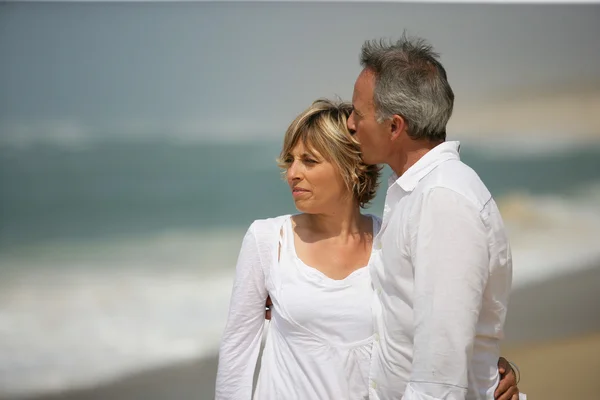 Gift par klädda i vitt med en promenad längs stranden — Stockfoto