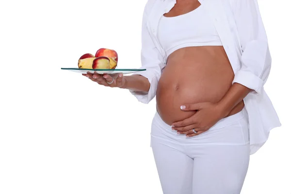 Беременная женщина с миской персиков — стоковое фото