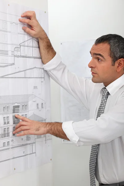 Arquiteto olhando para planos em uma parede — Fotografia de Stock