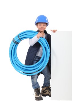 Young boy dressed as a plumber with a board left blank for your message clipart