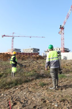 Field workers with cranes in the background clipart