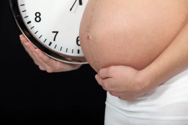 Беременная женщина с часами — стоковое фото