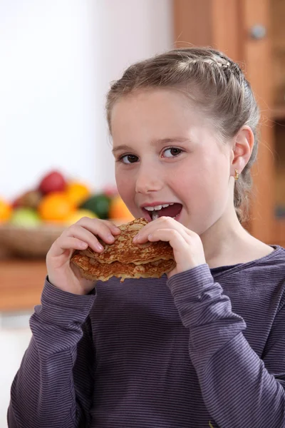 Маленькая девочка ест блинчики — стоковое фото