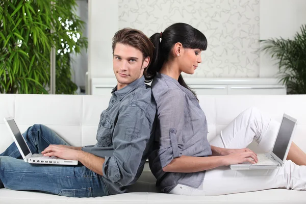 Paar sitzt Rücken an Rücken, während es seine Laptops benutzt — Stockfoto