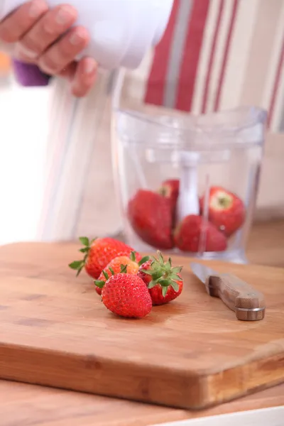 Kvinna sätta jordgubbarna i en mixer — Stockfoto