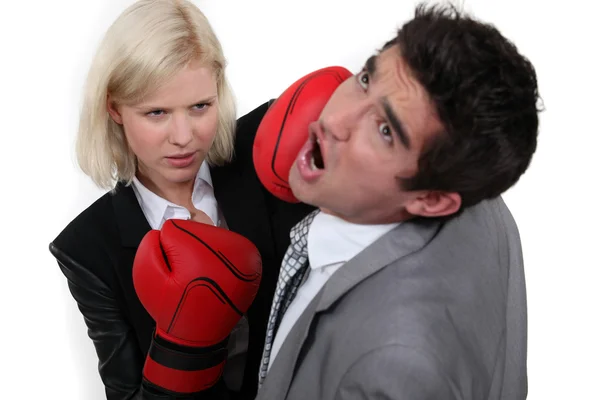 Mujer de negocios golpeando a un colega con un guante de boxeo —  Fotos de Stock