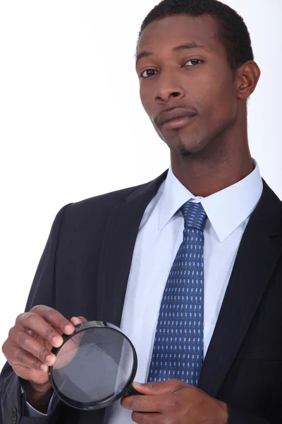 Africano americano em terno segurando uma lupa — Fotografia de Stock