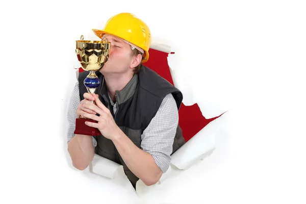 Ouvrier de la construction embrassant un trophée — Photo