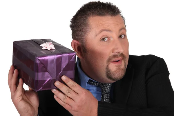 Affärsman försöker gissa vad som finns inuti sin gåva — Stockfoto