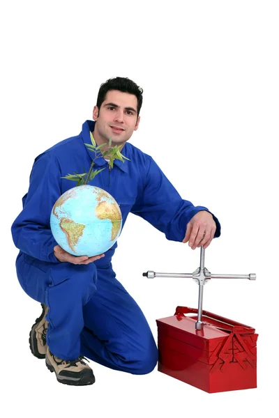 Механик на коленях с глобусом и гаечным ключом в руке — стоковое фото