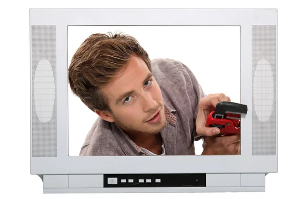 Young man with pliers behind a television screen — Stock Photo, Image