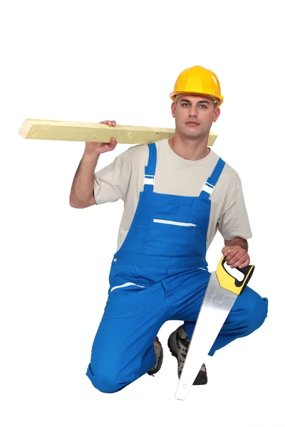Hantverkare innehar en planka och en såg — Stockfoto
