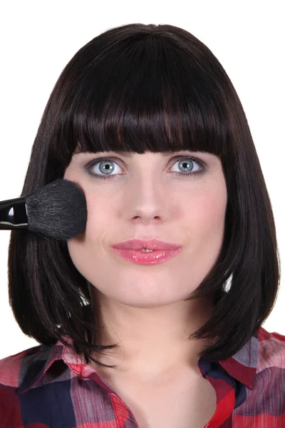 Woman applying blush to her cheekbones — Stock Photo, Image