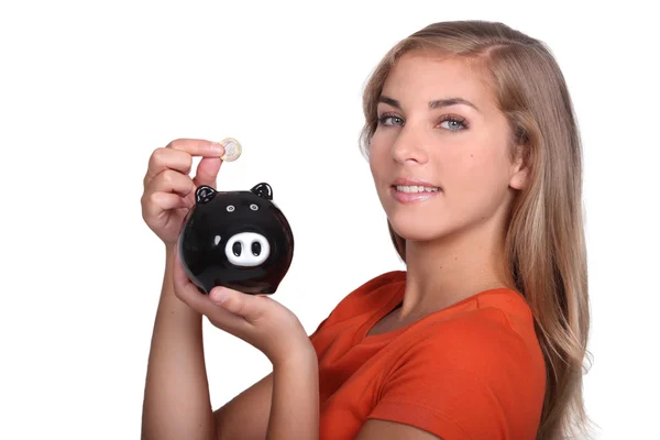 Teenager placing money in piggy bank — Stock Photo, Image