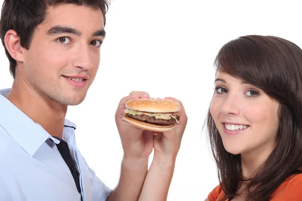 Pareja parada sosteniendo una hamburguesa con queso — Foto de Stock