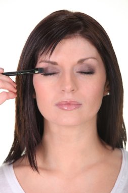 Woman applying eyeshadow clipart