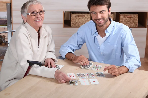 Jovens cartas de jogar com a mulher idosa — Fotografia de Stock