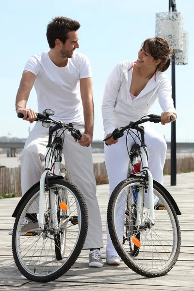 Пара в белом на велосипеде — стоковое фото