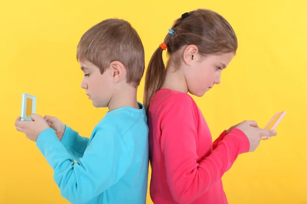 Brother and sister with hand-held video games — Stock Photo, Image
