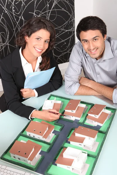 Агент и клиент рассматривают модель жилья — стоковое фото