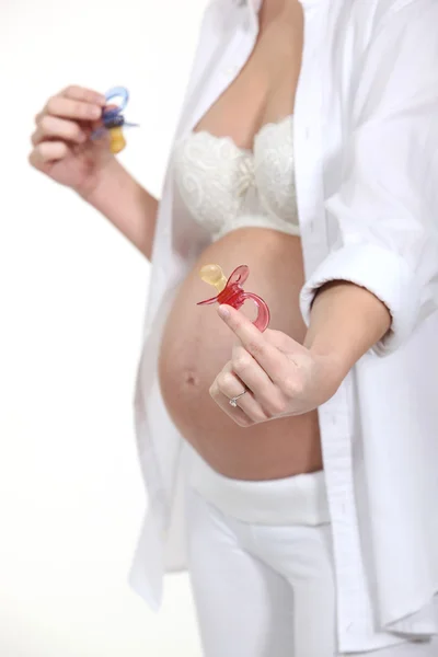 Pregnant woman showing pacifiers — Stock Photo, Image