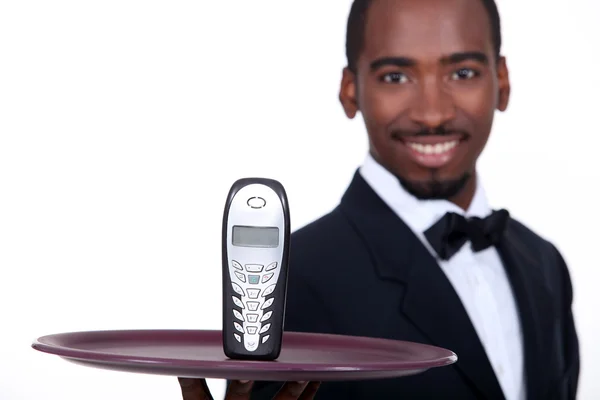 Black waiter showing a phone — Stock Photo, Image