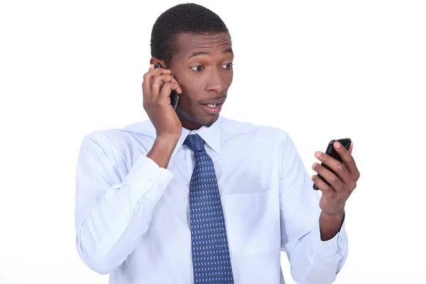 Chockad affärsman håller två telefoner — Stockfoto