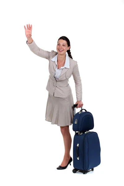 Woman with a suitcase waving at someone — Stock Photo, Image