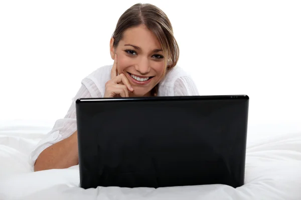 Brünette mit laptop legen im bett — Stockfoto