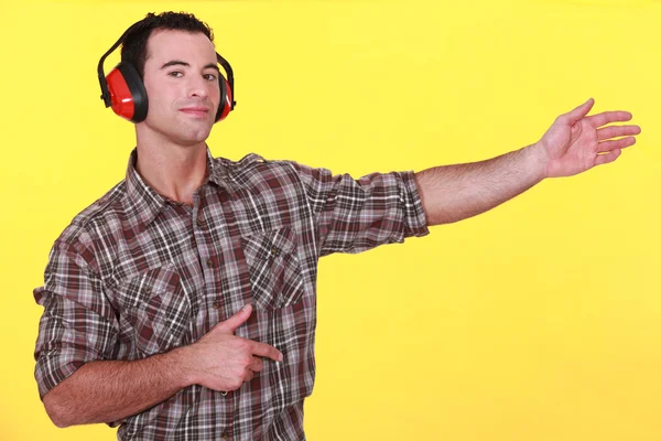 Homem usando protetores auriculares apresentando um objeto invisível — Fotografia de Stock